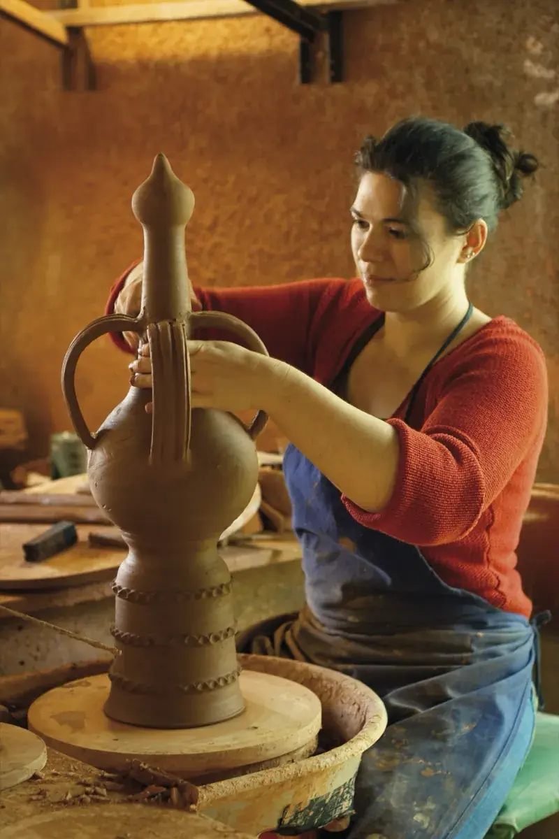 Céramiste façonnant un épi de faîtage dans son atelier